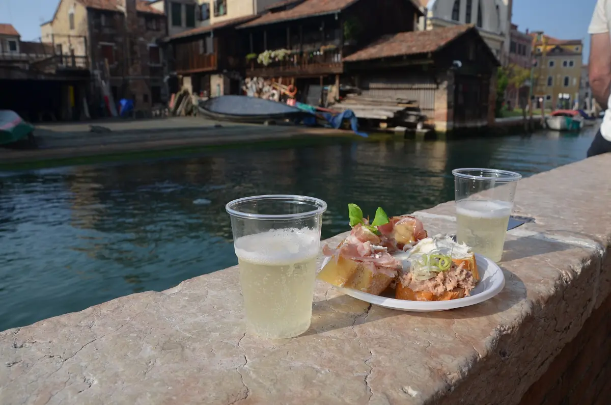Prosecco und Cicchetti auf einer Mauer am Wasser
